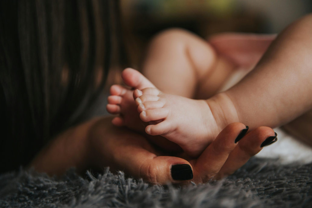 Baby's feet held up by a woman's hand.